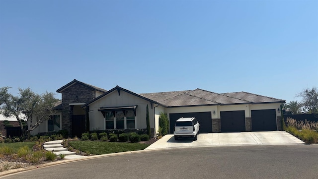 2189 E Strathspey Way, Fresno, CA 93730 - view of front facade with stone siding, concrete driveway, a garage, and board and batten siding