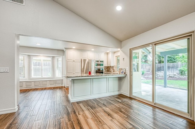 591 E Warwick Ave, Fresno, CA 93720 - kitchen featuring wood finished floors, a peninsula, white cabinetry, stainless steel appliances, and vaulted ceiling