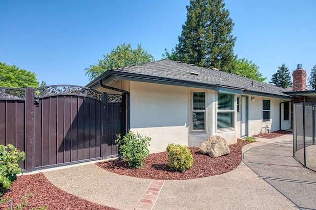 591 E Warwick Ave, Fresno, CA 93720 - view of side of property with a gate, stucco siding, roof with shingles, and a chimney