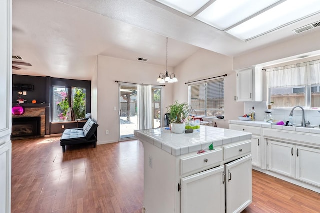 539 Chablis Ave, Madera, CA 93637 - kitchen with tile counters, white cabinets, open floor plan, a chandelier, and light wood finished floors