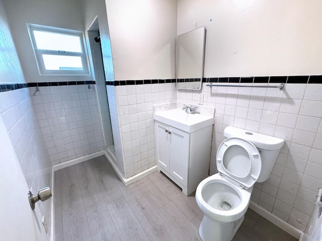 1741 N Blythe Ave, Fresno, CA 93722 - full bath with tile walls, tiled shower, vanity, a wainscoted wall, and wood finished floors
