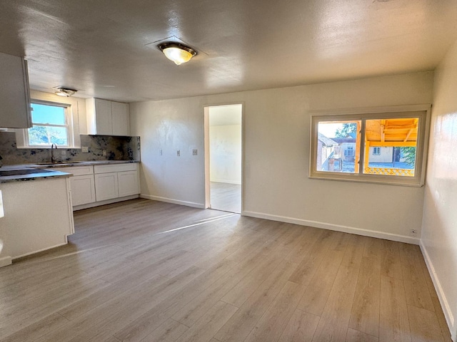 1741 N Blythe Ave, Fresno, CA 93722 - kitchen with decorative backsplash, white cabinets, and light wood finished floors