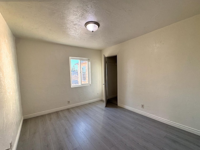 1741 N Blythe Ave, Fresno, CA 93722 - spare room with dark wood-type flooring, a textured ceiling, and a textured wall