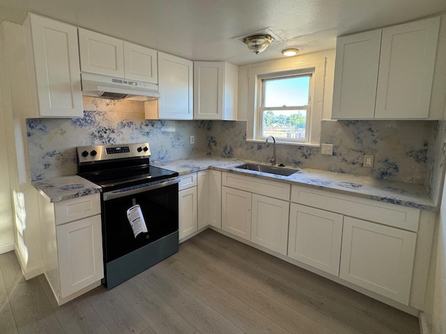 1741 N Blythe Ave, Fresno, CA 93722 - kitchen with stainless steel range with electric stovetop, under cabinet range hood, wood finished floors, white cabinets, and tasteful backsplash