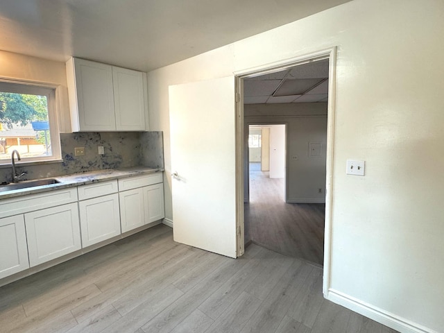 1741 N Blythe Ave, Fresno, CA 93722 - kitchen featuring light wood finished floors, white cabinetry, decorative backsplash, light countertops, and a paneled ceiling