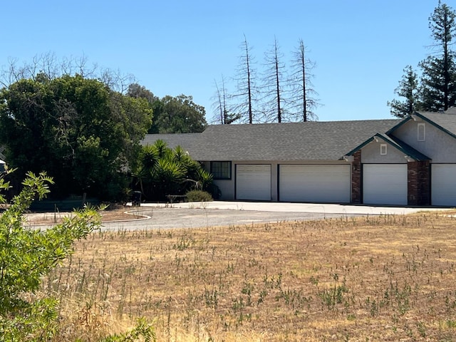 16564 Monreal Rd, Madera, CA 93636 - view of front of home with an attached garage, roof with shingles, driveway, and brick siding
