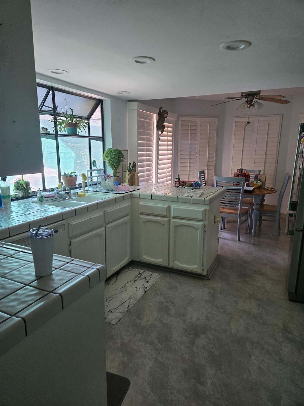 7762 N 7th St, Fresno, CA 93720 - kitchen featuring tile countertops, ceiling fan, freestanding refrigerator, and white cabinets