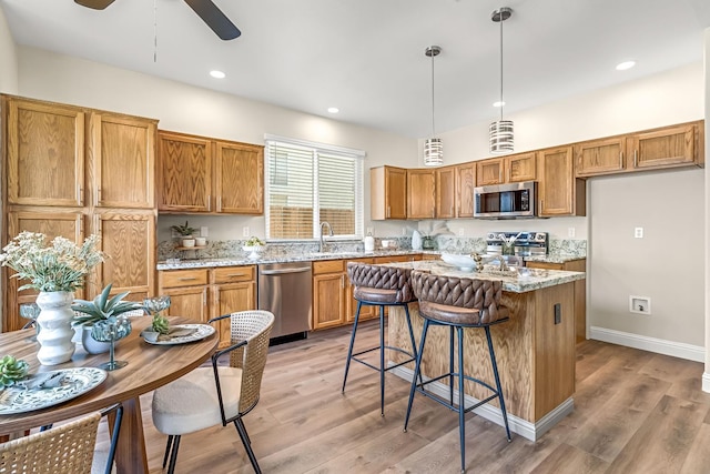 2234 E Serena Ave, Fresno, CA 93720 - kitchen with appliances with stainless steel finishes, brown cabinetry, light wood-type flooring, a kitchen island, and recessed lighting