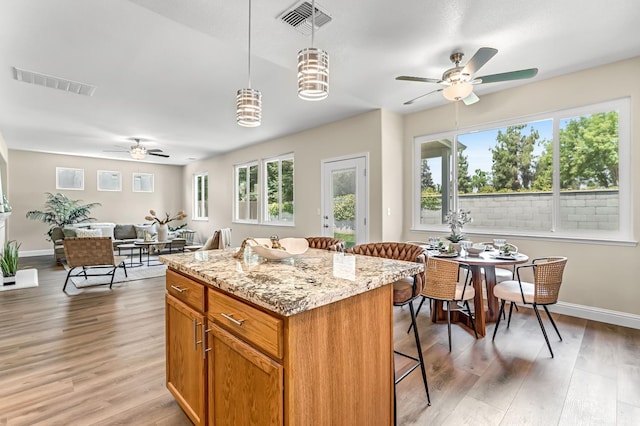 2234 E Serena Ave, Fresno, CA 93720 - kitchen with ceiling fan, a center island, light wood finished floors, and a kitchen breakfast bar