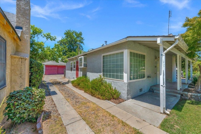 1461 N Harrison Ave, Fresno, CA 93728 - view of side of property with a porch, an outbuilding, stucco siding, crawl space, and a detached garage