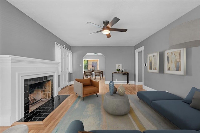 1461 N Harrison Ave, Fresno, CA 93728 - living area with ceiling fan, arched walkways, wood finished floors, and a tile fireplace