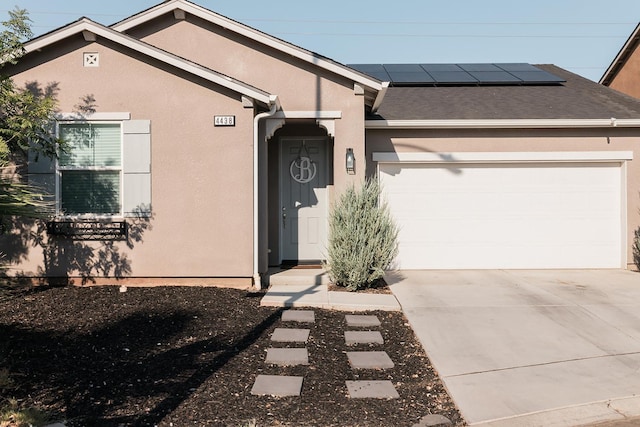 4438 N Sandrini Ave, Fresno, CA 93723 - view of front of property featuring an attached garage, stucco siding, roof mounted solar panels, and concrete driveway