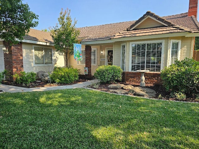 1509 Princeton Ave, Madera, CA 93637 - view of front of house featuring brick siding, a front yard, and a tile roof