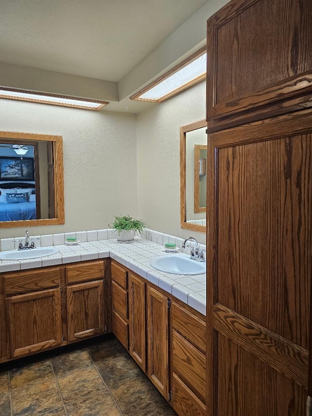 1509 Princeton Ave, Madera, CA 93637 - ensuite bathroom featuring double vanity, stone finish flooring, and a textured wall