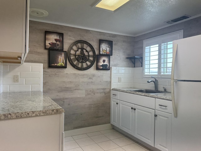 4741 W Mckinley Ave, Fresno, CA 93722 - kitchen with freestanding refrigerator, light countertops, light tile patterned floors, white cabinetry, and ornamental molding