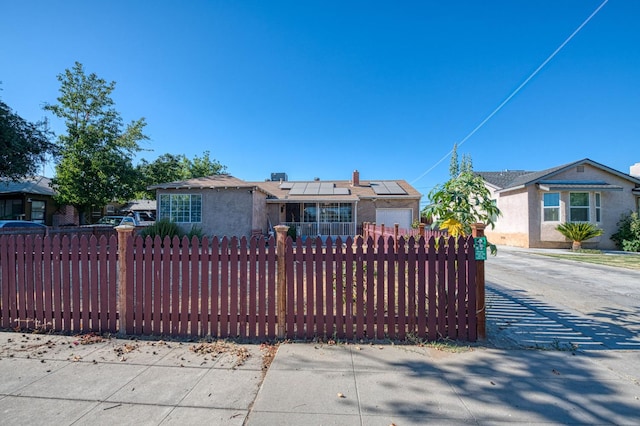 2323 E University, Fresno, CA 93703 - view of front of home with a fenced front yard, roof mounted solar panels, concrete driveway, and stucco siding