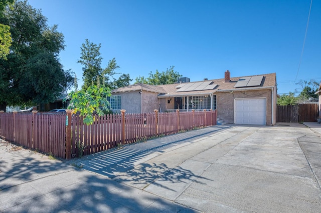 2323 E University, Fresno, CA 93703 - view of front of property featuring a fenced front yard, concrete driveway, roof mounted solar panels, and a chimney