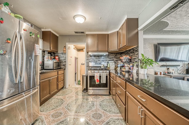 2323 E University, Fresno, CA 93703 - kitchen featuring stainless steel appliances, decorative backsplash, brown cabinets, a textured ceiling, and light tile patterned flooring