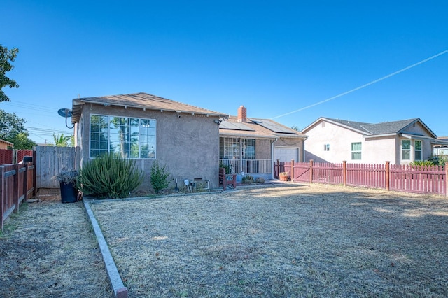 2323 E University, Fresno, CA 93703 - back of house with roof mounted solar panels, a fenced backyard, stucco siding, and a chimney