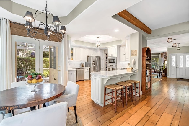 6609 N Dover Ct, Fresno, CA 93711 - kitchen featuring a chandelier, a peninsula, white cabinetry, a breakfast bar area, and stainless steel appliances