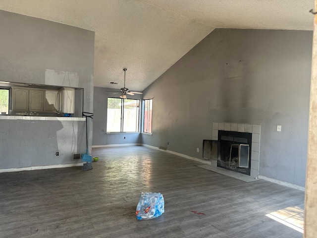 2244 N Prospect, Fresno, CA 93722 - unfurnished living room featuring high vaulted ceiling, dark wood-style floors, ceiling fan, a tiled fireplace, and a textured ceiling