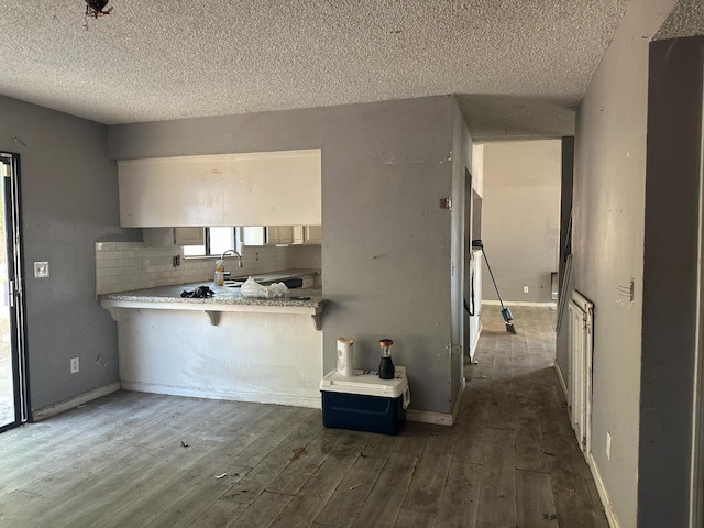 2244 N Prospect, Fresno, CA 93722 - kitchen with a textured ceiling, dark wood-style flooring, a kitchen bar, tasteful backsplash, and a peninsula