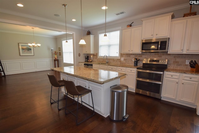 kitchen with an inviting chandelier, dark wood-type flooring, white cabinetry, stainless steel appliances, and pendant lighting