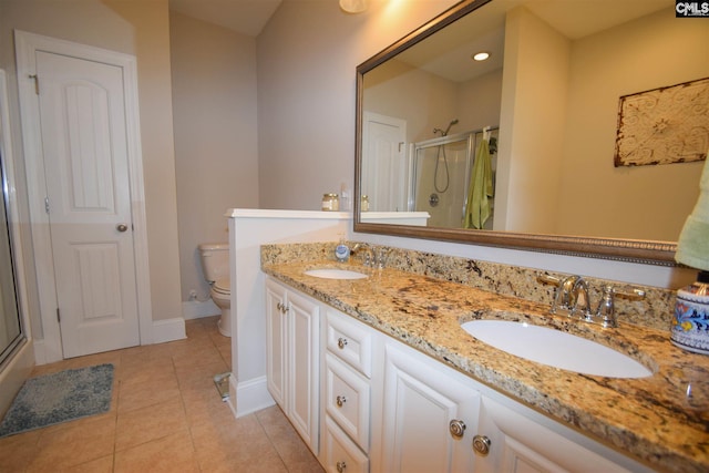 bathroom with double sink, tile floors, a shower with door, toilet, and oversized vanity