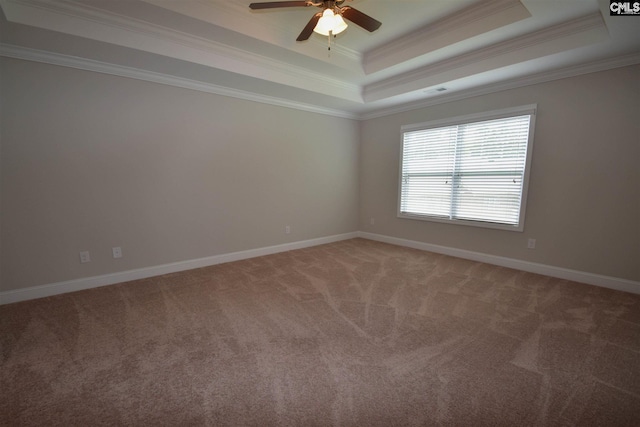 unfurnished room with dark colored carpet, a raised ceiling, ornamental molding, and ceiling fan