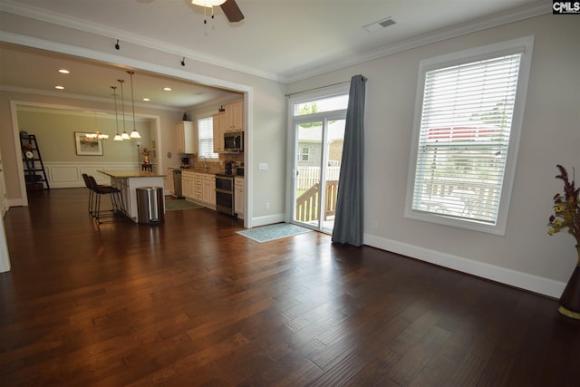 living room featuring dark hardwood / wood-style flooring, crown molding, ceiling fan with notable chandelier, and sink