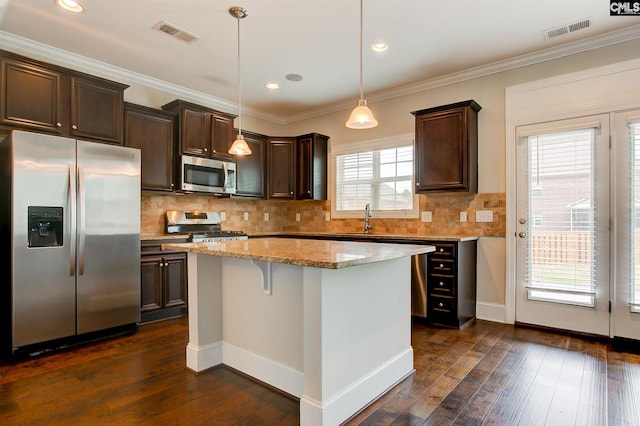 kitchen featuring hanging light fixtures, stainless steel appliances, dark hardwood / wood-style flooring, and a wealth of natural light