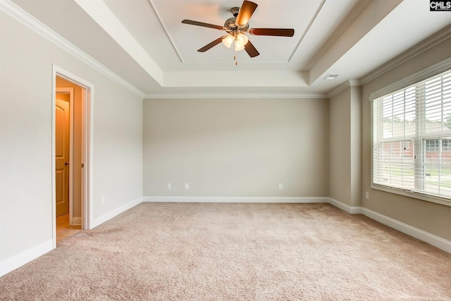 carpeted empty room with a raised ceiling, ornamental molding, and ceiling fan