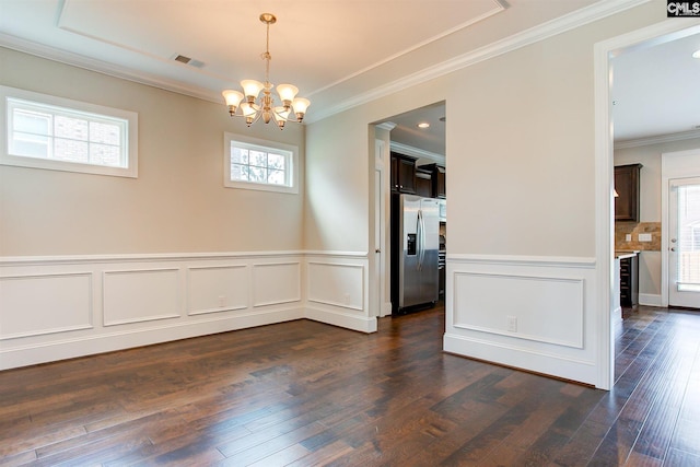 empty room featuring dark hardwood / wood-style flooring, ornamental molding, and a chandelier