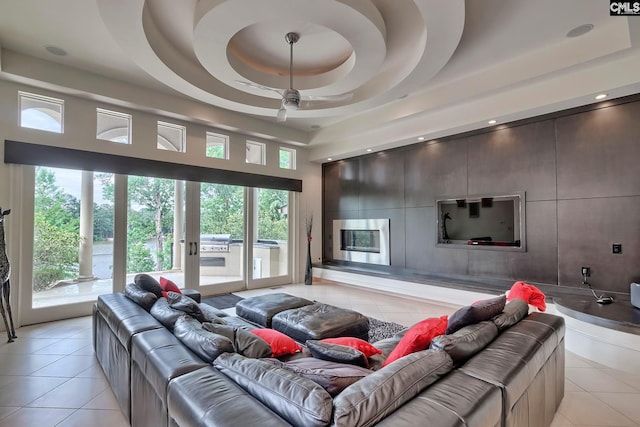 living room with plenty of natural light, a raised ceiling, and light tile floors