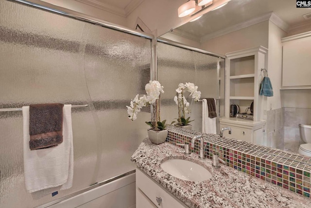 full bathroom featuring shower / bath combination with glass door, toilet, large vanity, and crown molding