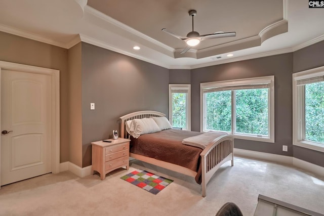 bedroom featuring light carpet, a tray ceiling, ornamental molding, and ceiling fan