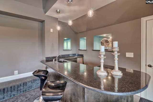 kitchen with pendant lighting, sink, dark stone counters, and carpet floors