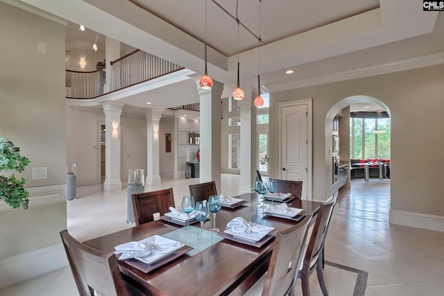 dining room with a raised ceiling, decorative columns, light tile floors, and a towering ceiling