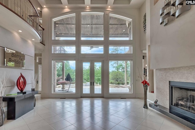 interior space with a tiled fireplace, plenty of natural light, french doors, and a high ceiling