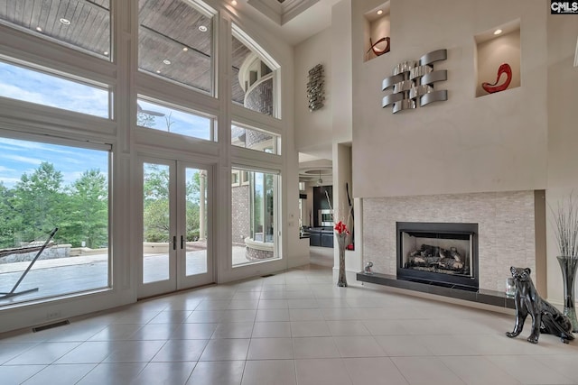 unfurnished living room with french doors, light tile flooring, and a high ceiling