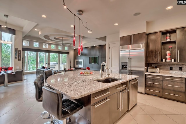 kitchen featuring a breakfast bar, an island with sink, stainless steel appliances, pendant lighting, and sink