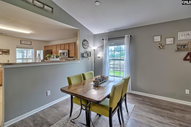 dining room featuring hardwood / wood-style flooring, vaulted ceiling, and a healthy amount of sunlight