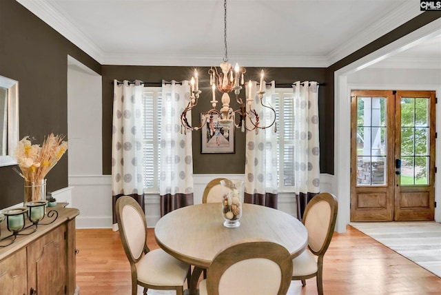 dining space featuring a chandelier, ornamental molding, light wood-type flooring, and french doors