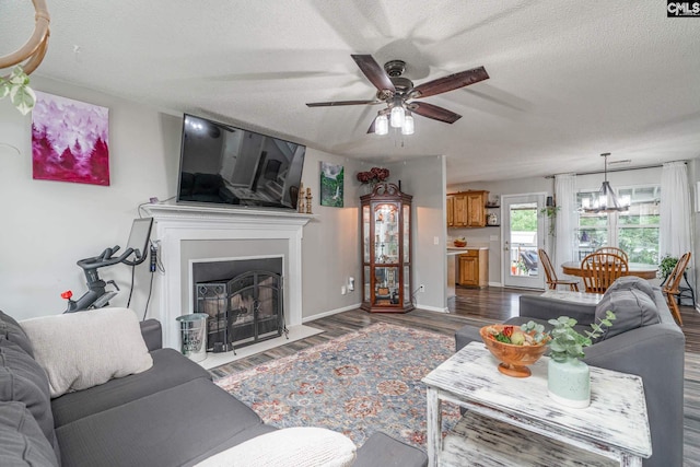 living room with a textured ceiling, dark hardwood / wood-style floors, and ceiling fan with notable chandelier