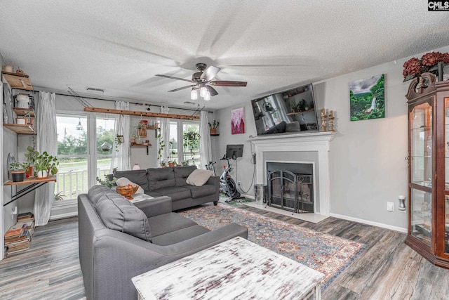 living room featuring ceiling fan, dark hardwood / wood-style floors, and a textured ceiling