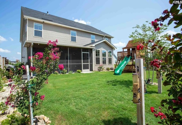 rear view of house with a lawn, a playground, and a sunroom