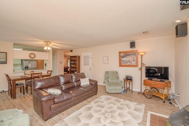 living room with light hardwood / wood-style floors, ceiling fan, and a textured ceiling