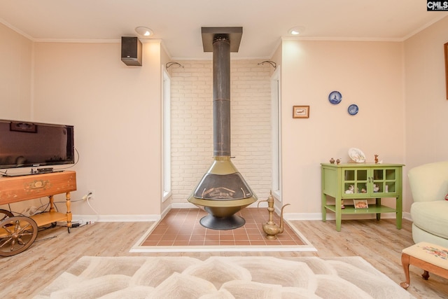 interior space featuring ornamental molding, brick wall, a wood stove, and light hardwood / wood-style flooring