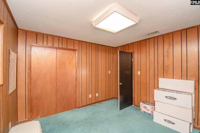 unfurnished office featuring wooden walls, light carpet, and a textured ceiling