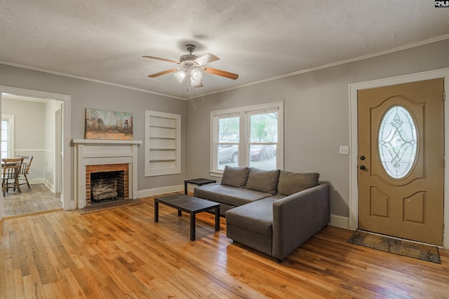 living room featuring a brick fireplace, ceiling fan, built in features, a textured ceiling, and light wood-type flooring